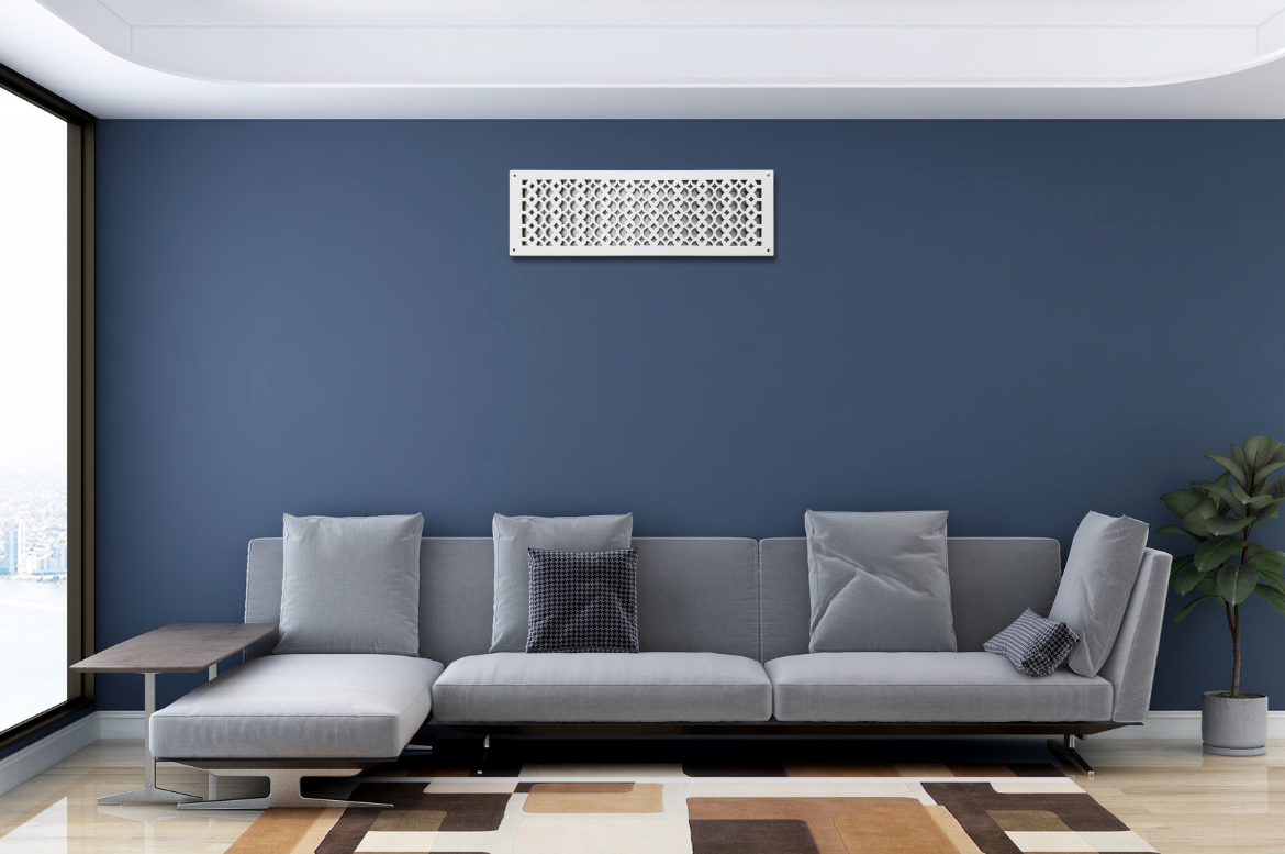 A modern living room with a gray sectional sofa, blue accent wall, geometric art above the couch, a potted plant, and a large window with city views. The floor has a cream and brown patterned rug.