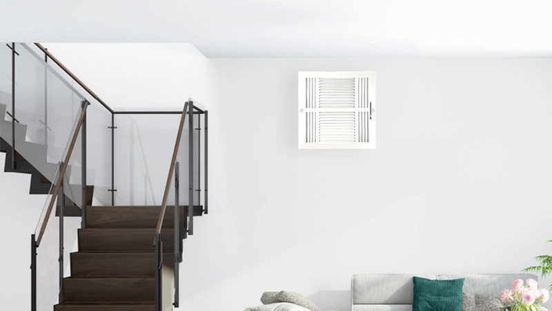 A modern living room with a dark wooden staircase featuring glass railings, a gray couch with teal and white pillows, and a white air vent on the wall. The space is bright with white walls and minimalist decor.