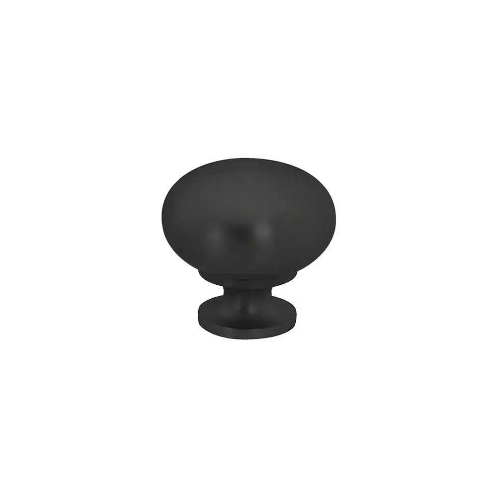 A matte black round cabinet knob by Taymor Industries, featuring a smooth dome top, short cylindrical base, modern design, and sturdy zinc die-cast construction, is centered on a plain white background.