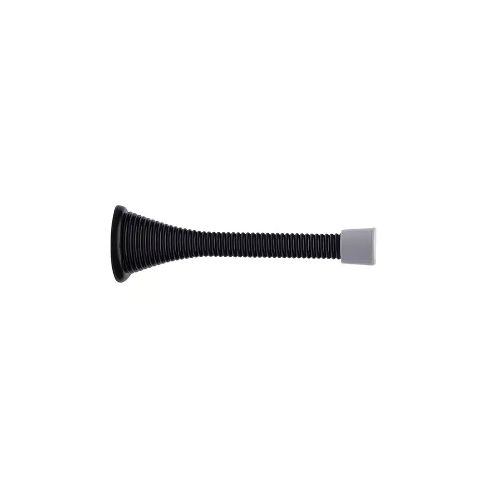 A Taymor Industries black spring door stop with a metal base and wide circular left end, steel spring (24mm wire diameter), and gray rubber tip on the right, isolated on a white background.