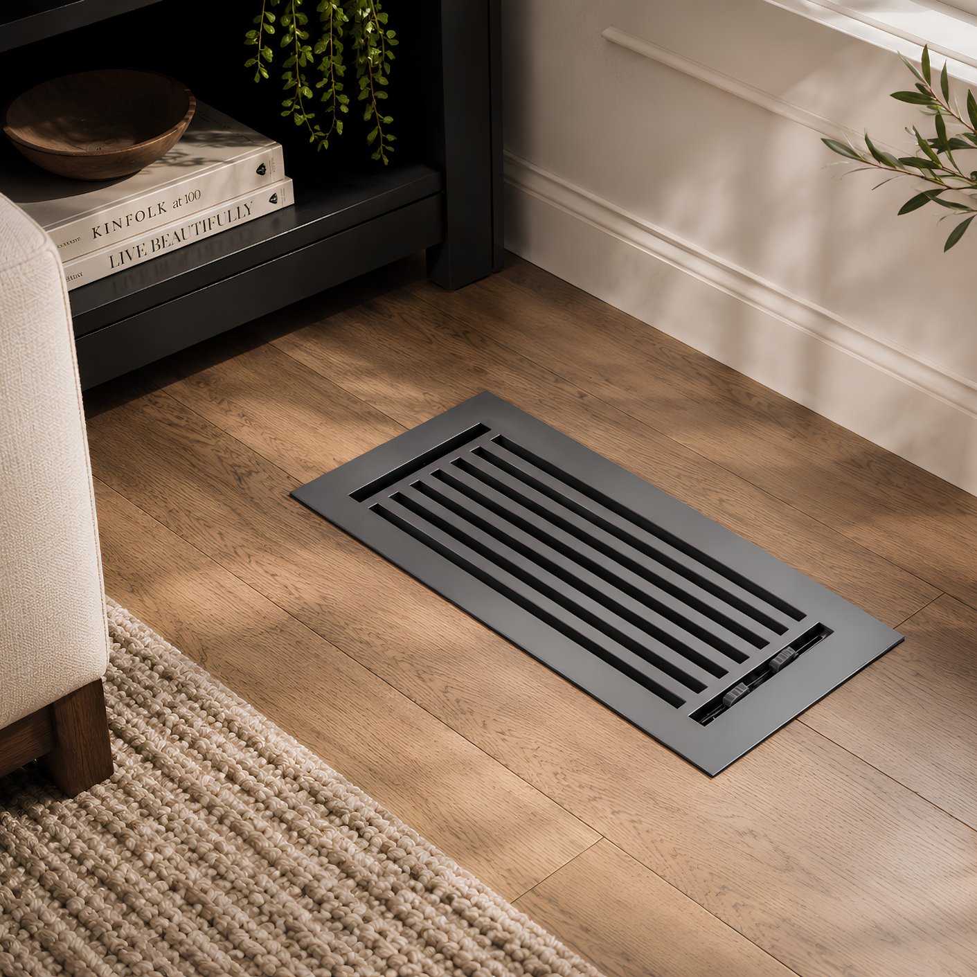 Floor vent on a wooden floor in a room with books and a plant.