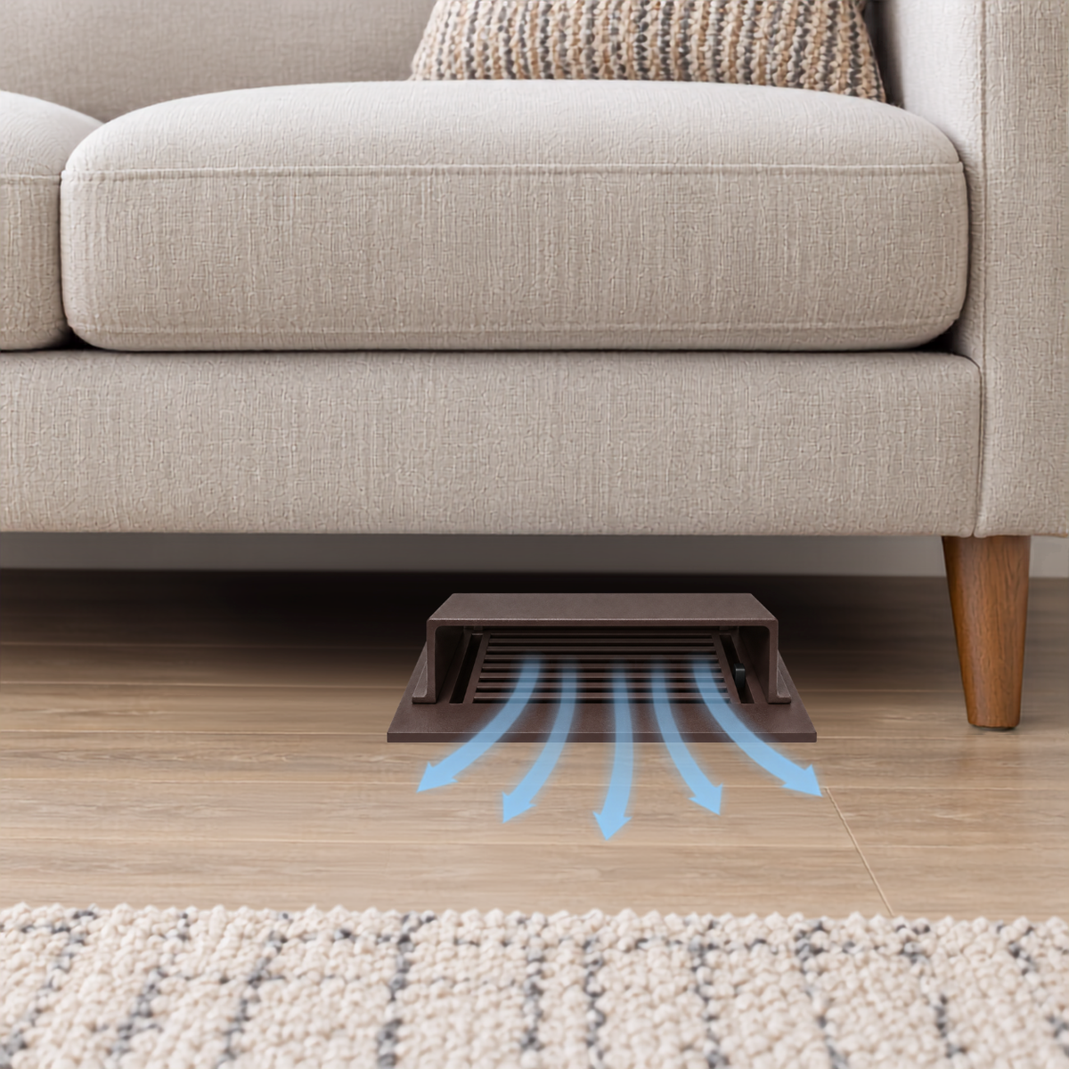 A brown deflector installed under a beige sofa on a wood floor.
