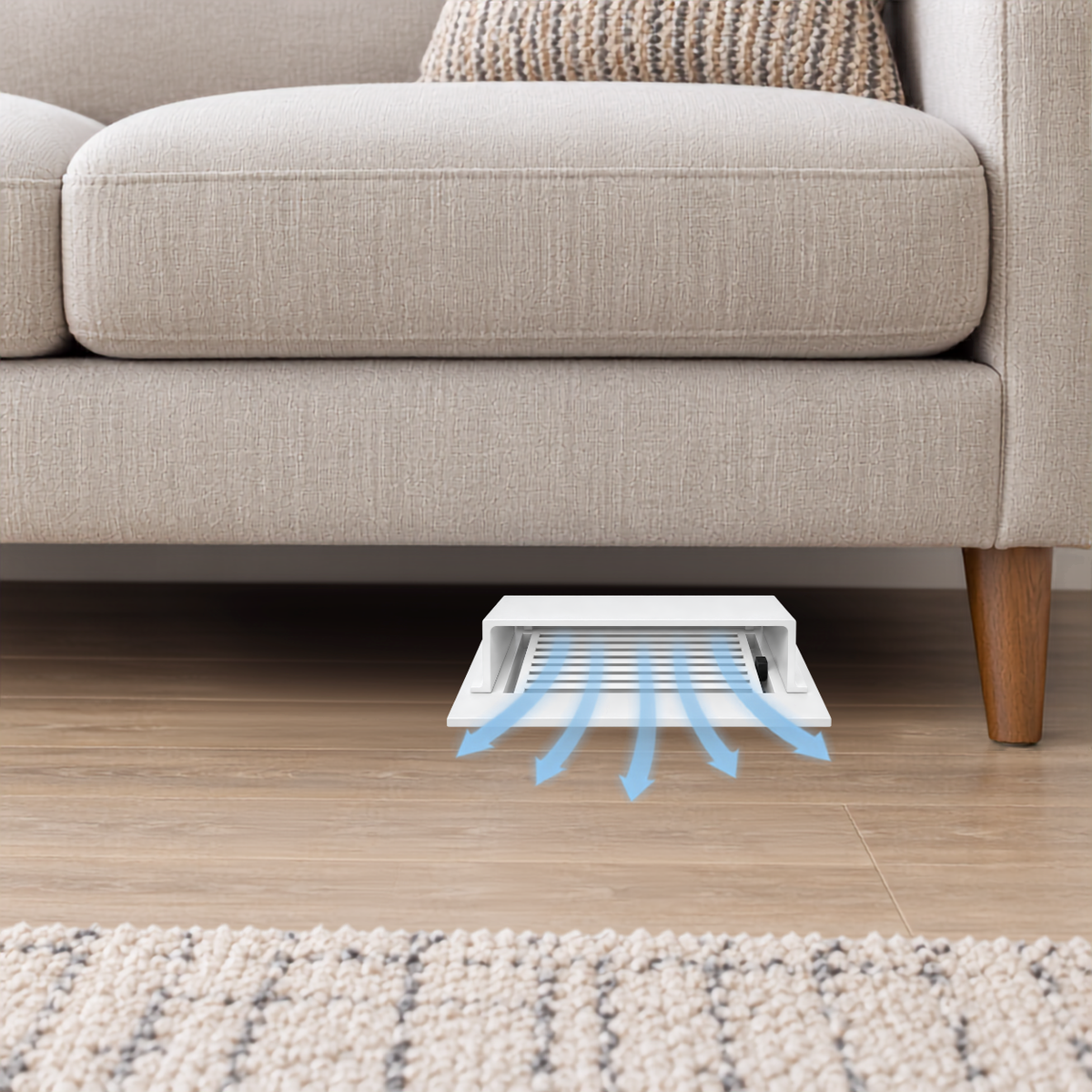 A white deflector installed under a beige sofa on a wood floor.
