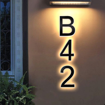 A wall lit by a lamp displays large black letters and numbers vertically reading B42, with plants visible at the bottom left corner.