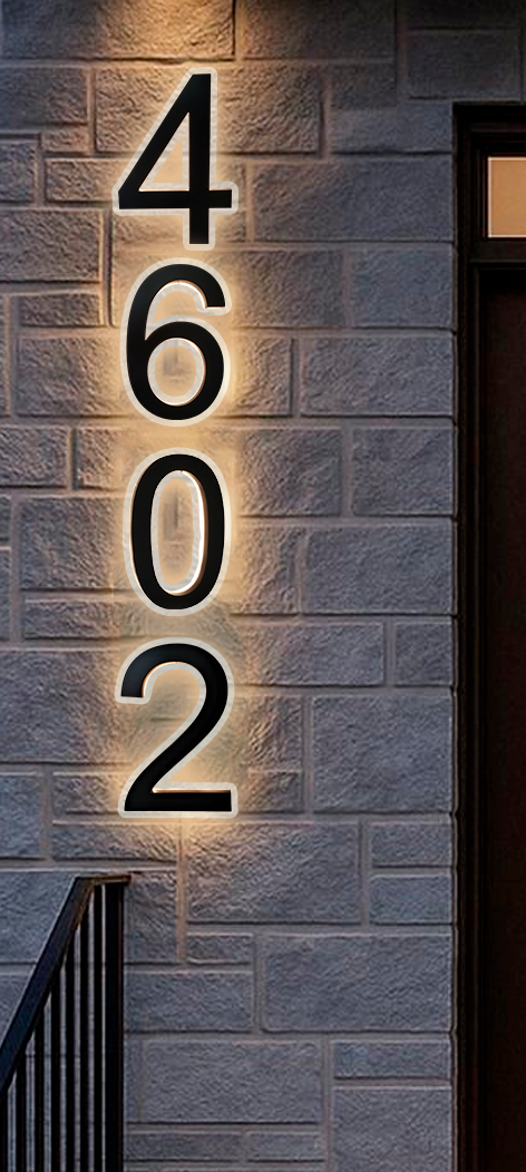 Large black house numbers 4602 are mounted vertically on a light-colored brick wall near a door, each number illuminated with a soft backlight.