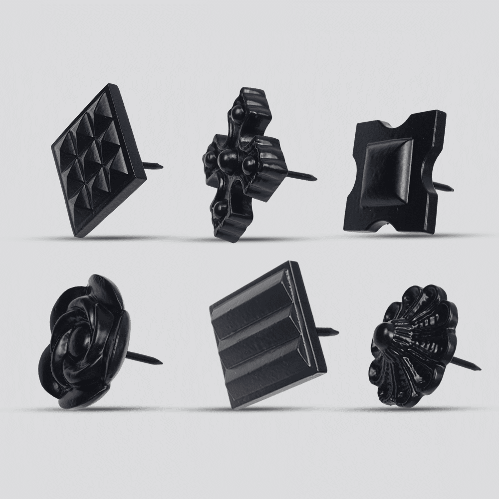 Six black decorative upholstery tacks with unique shapes and patterns, including geometric, floral, and abstract designs, displayed against a light gray background.