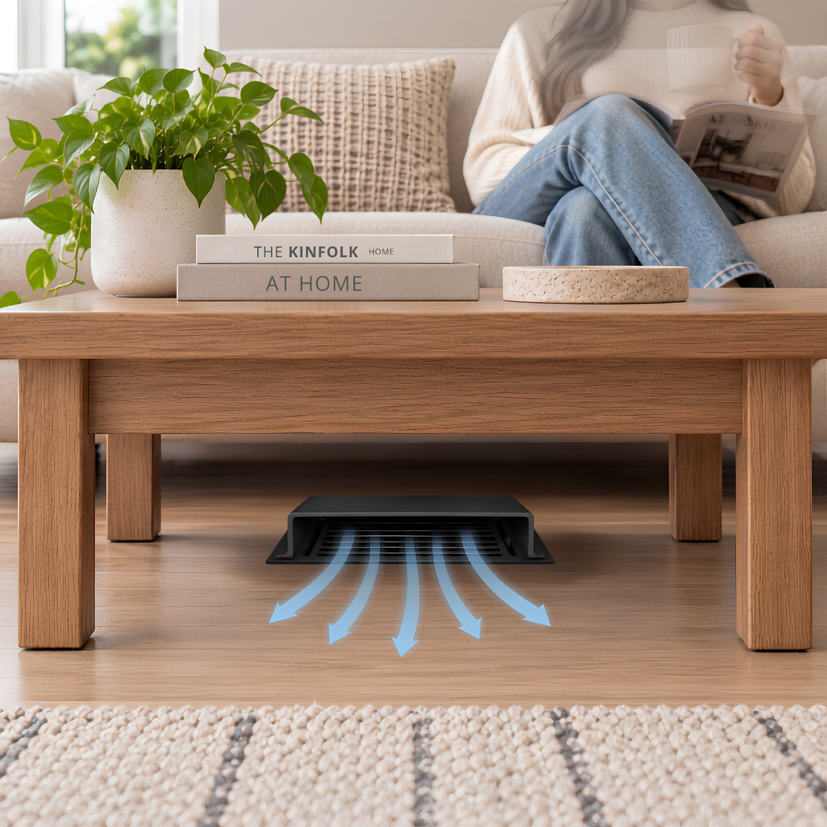 A matte black deflector installed on a wooden floor beneath a wooden coffee table in a modern living room.

